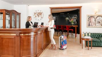 A reception area with a wooden reception desk, a world map on the wall, and a green sofa in the background.