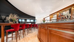 Un espace bar avec un comptoir en bois, des chaises rouges et un sol en marbre.