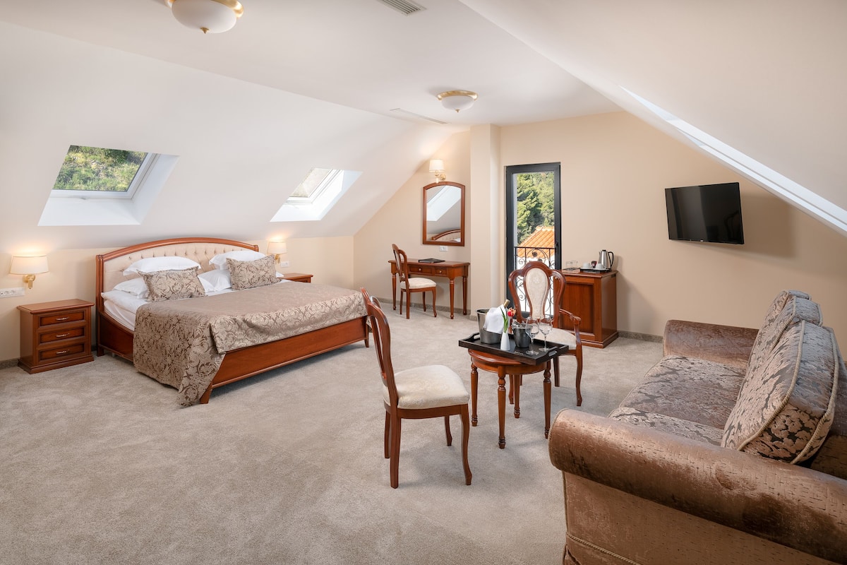 A bedroom with a bed, a desk, a chair, a sofa, and a TV.