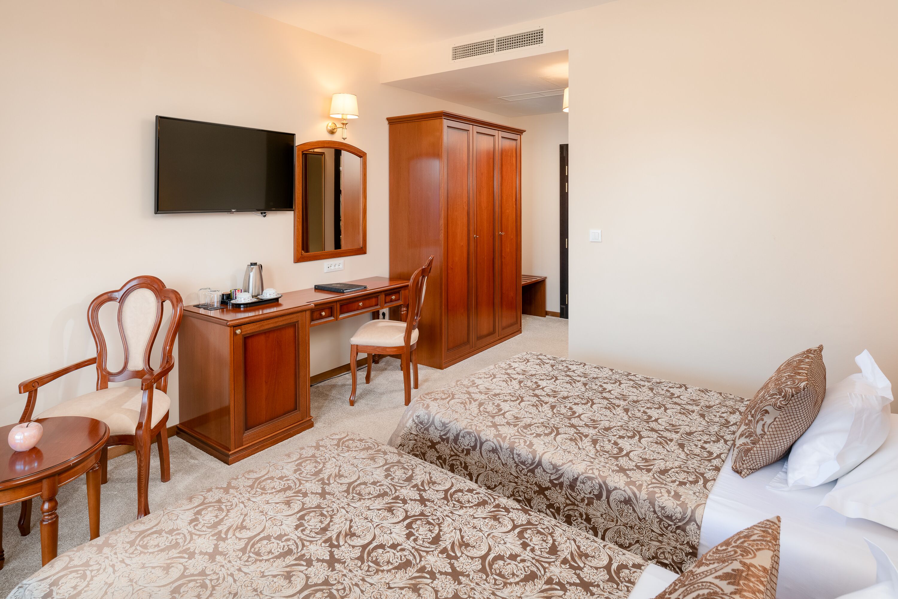 Ein Hotelzimmer mit Bett, Schreibtisch, Stuhl, Kleiderschrank und Fernseher.