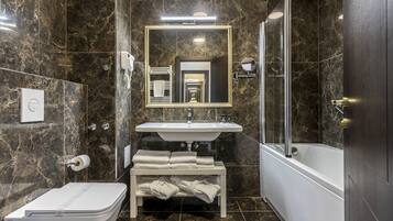 A modern bathroom with a marble floor, a white toilet, a sink, a mirror, and a shower.