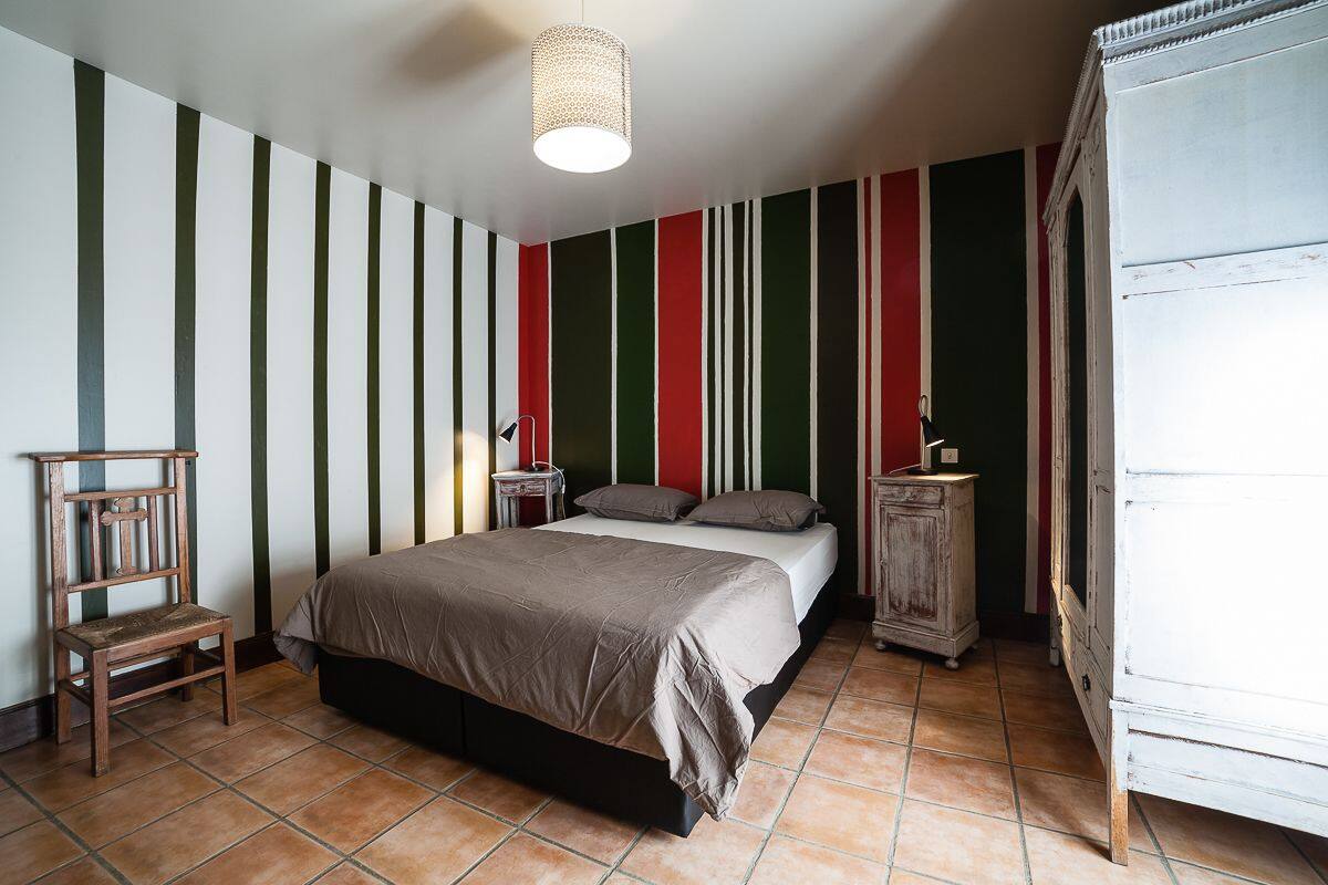 Een slaapkamer met een bed, een houten stoel, een nachtkastje en een kledingkast.