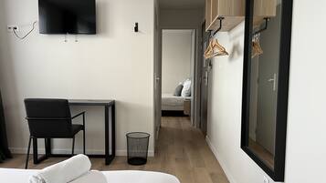 Ein modernes Hotelzimmer mit Bett, Schreibtisch, Stuhl, Fernseher und Kleiderschrank.