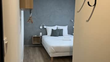 Une chambre à coucher comprenant un lit, des tables de chevet, un luminaire suspendu et un porte-serviettes fixé au mur.