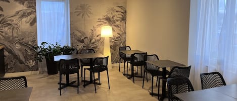 A dining area with a table and chairs, a floor lamp, and a wall with a tropical mural.