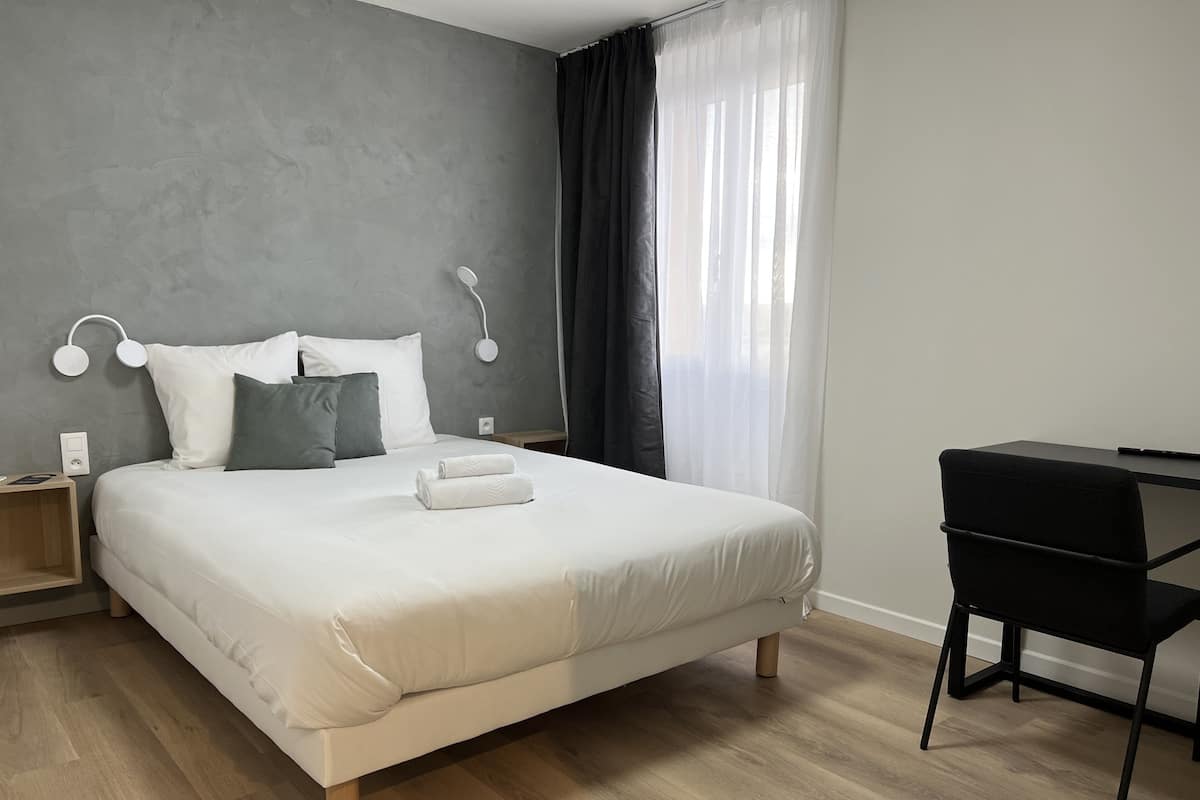 A modern bedroom with a large bed, a desk, and a chair.