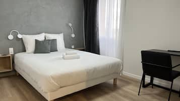 A modern bedroom with a large bed, a desk, and a chair.