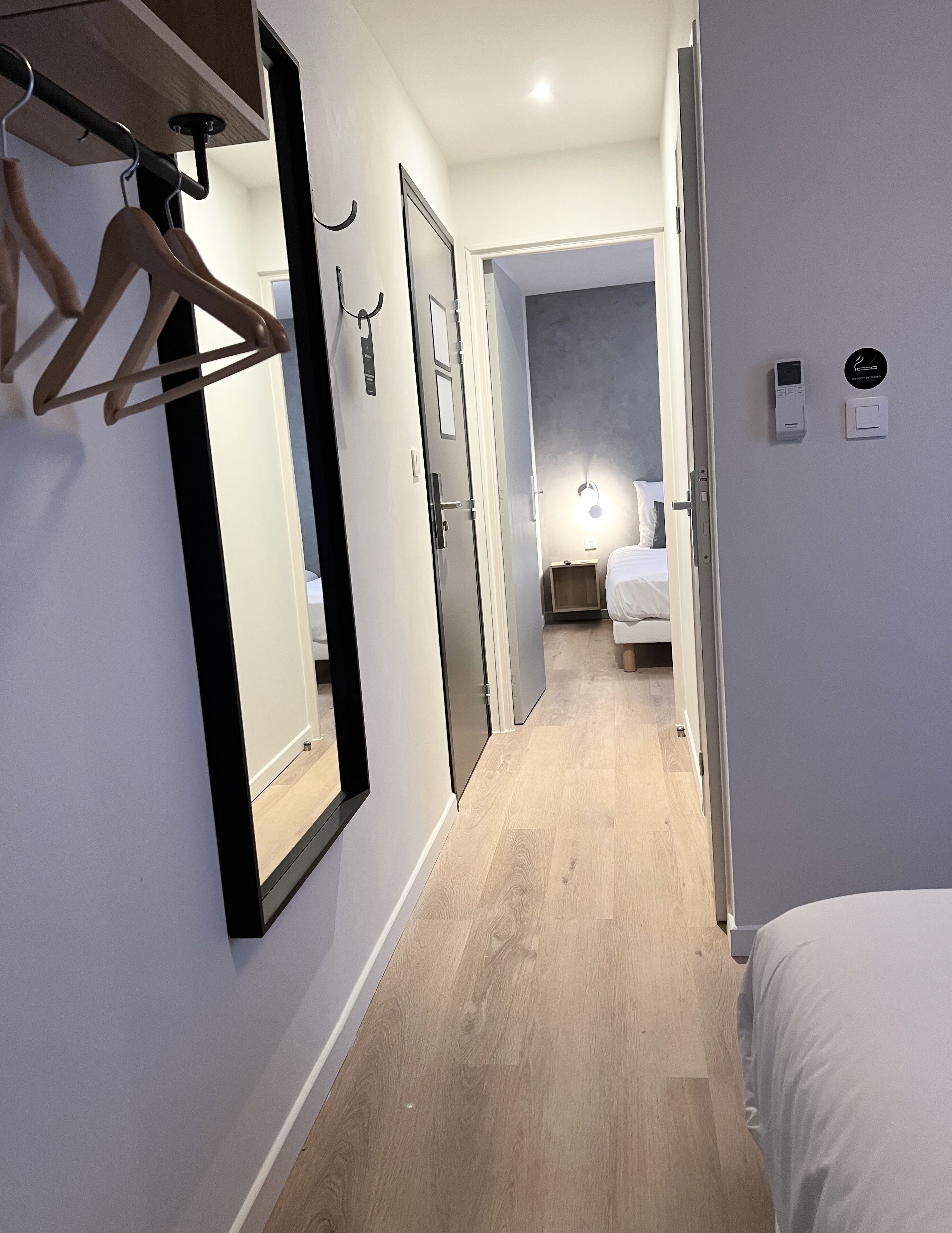 Pasillo de hotel con una cama, un armario y un espejo.