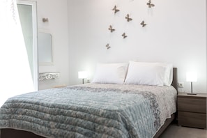 Un dormitorio con cama, mesitas de noche, un espejo montado en la pared y decoración de mariposas.
