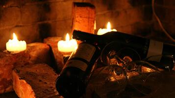 A bottle of wine, a glass, and lit candles on a brick surface.