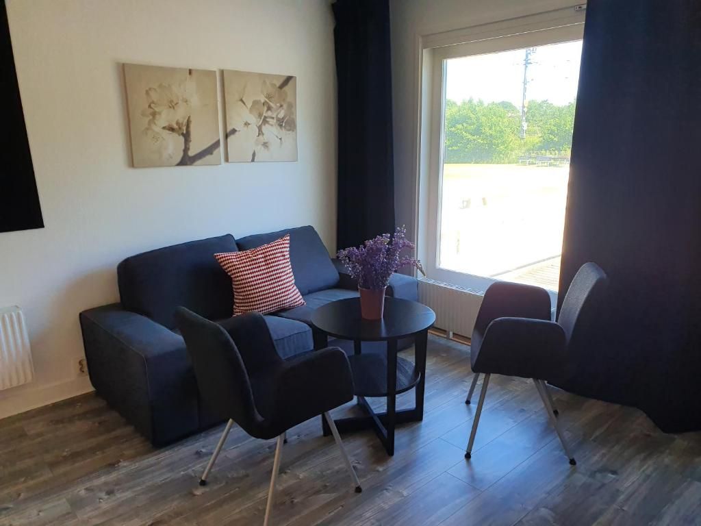A modern living room with a sofa, two armchairs, a small round table, and a potted plant.