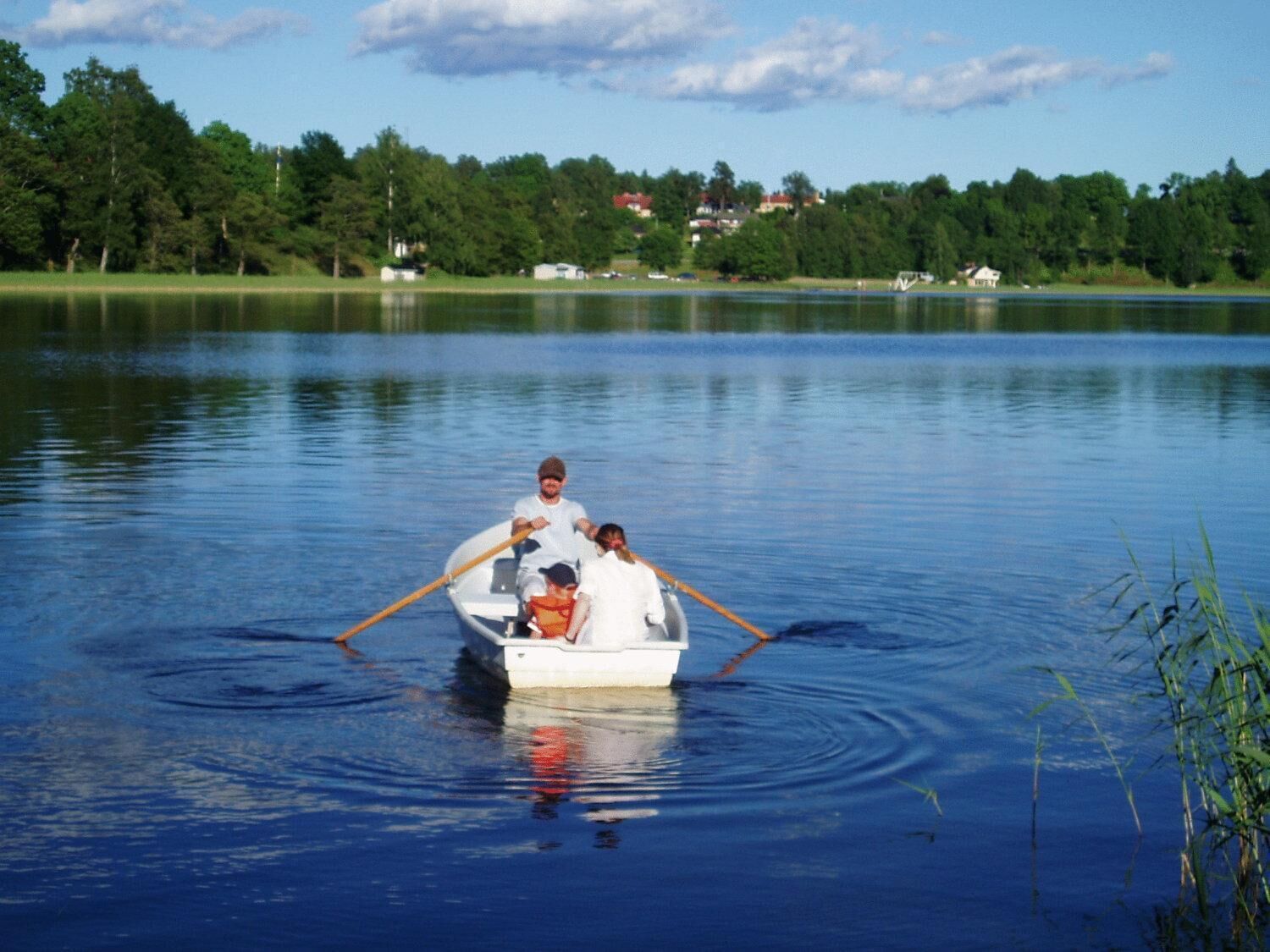Una lancha pequeña en un lago tranquilo con una familia.