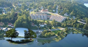 Vue aérienne d’un quartier résidentiel avec un grand ensemble d’immeubles, un lac et une végétation luxuriante.