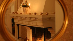 A fireplace with a white mantel and a vase of flowers. - Hotell Dalsland (Ed)