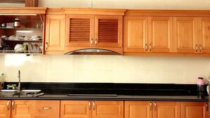 A kitchen with wooden cabinets, a black countertop, and a stainless steel range hood. - Sky Halong Hotel (Bai Chay)