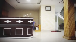 A reception area with a curved counter, a clock on the wall, and a staircase leading to another floor. - Sky Halong Hotel (Bai Chay)