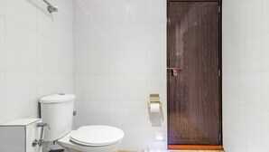 Ein Badezimmer mit Toilette, Dusche und Holztür.