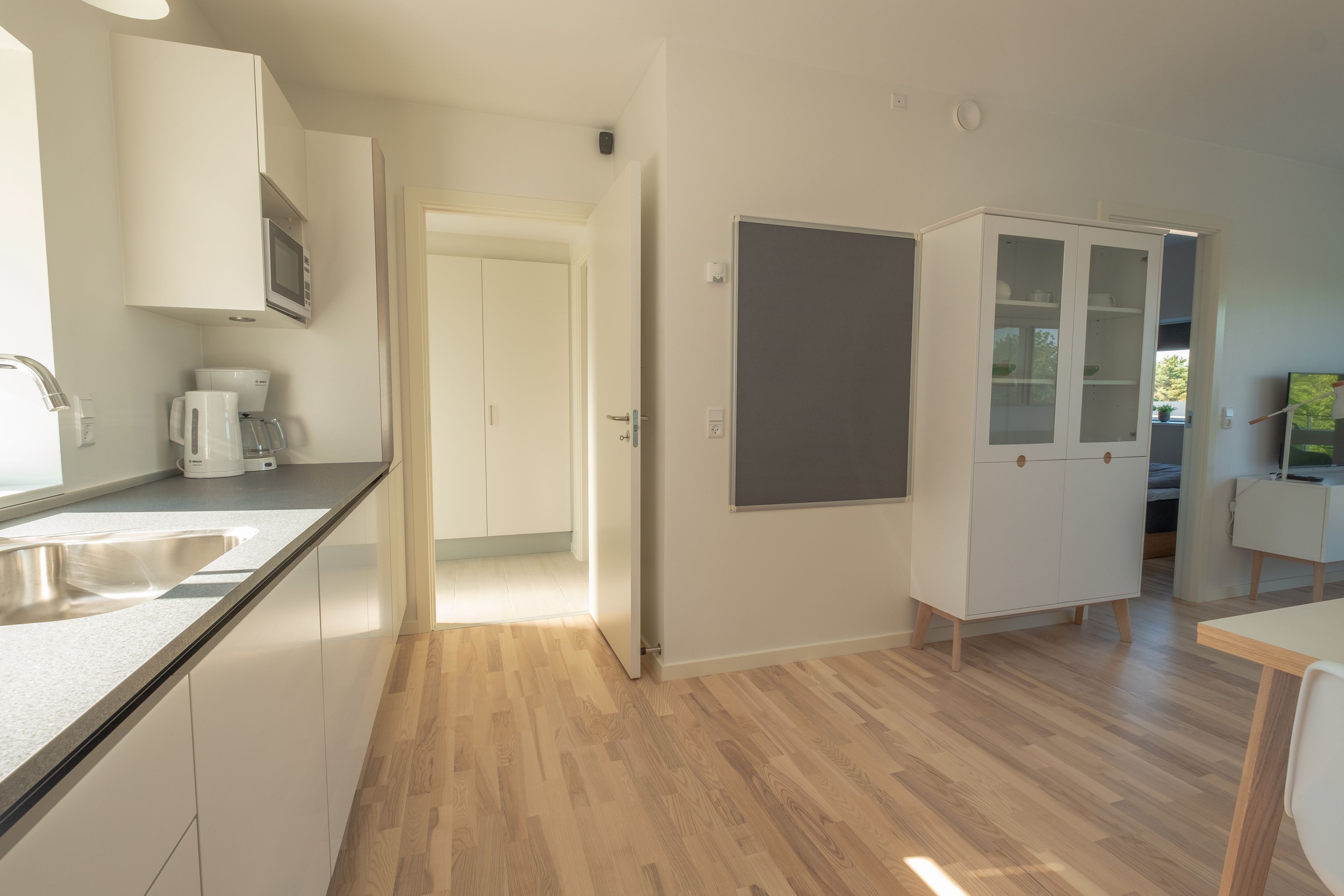 A modern kitchen with white cabinets, a built-in microwave, and a coffee maker.
