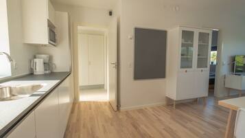 A modern kitchen with white cabinets, a built-in microwave, and a coffee maker.