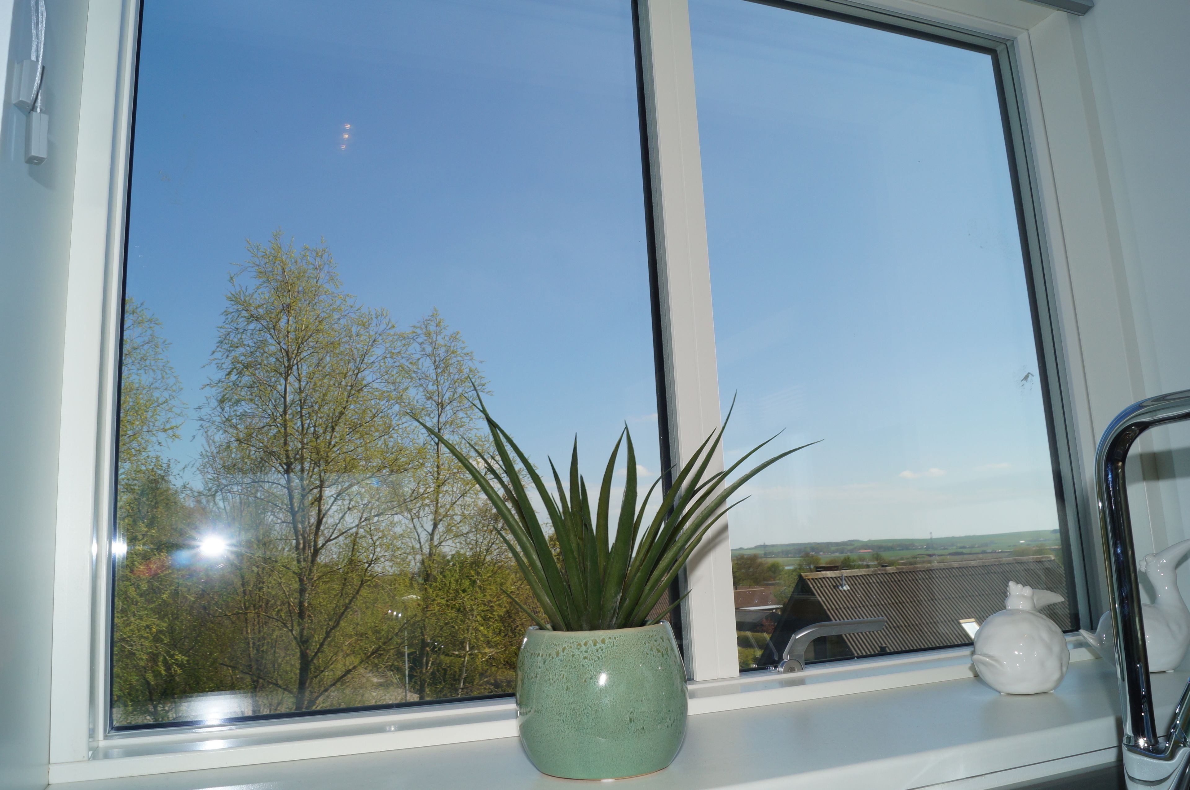 A window with a potted plant and a small vase on the windowsill.
