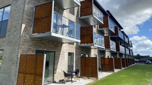 A modern apartment building with multiple balconies, large windows, and a grassy courtyard. - Aalborg Hotel Apartments (Aalborg)