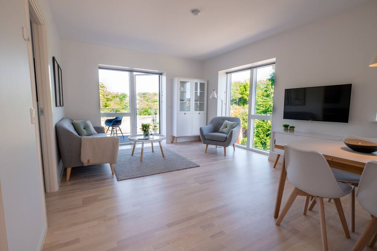 Un salon moderne comprenant un canapé, des fauteuils, une table à manger et un téléviseur.