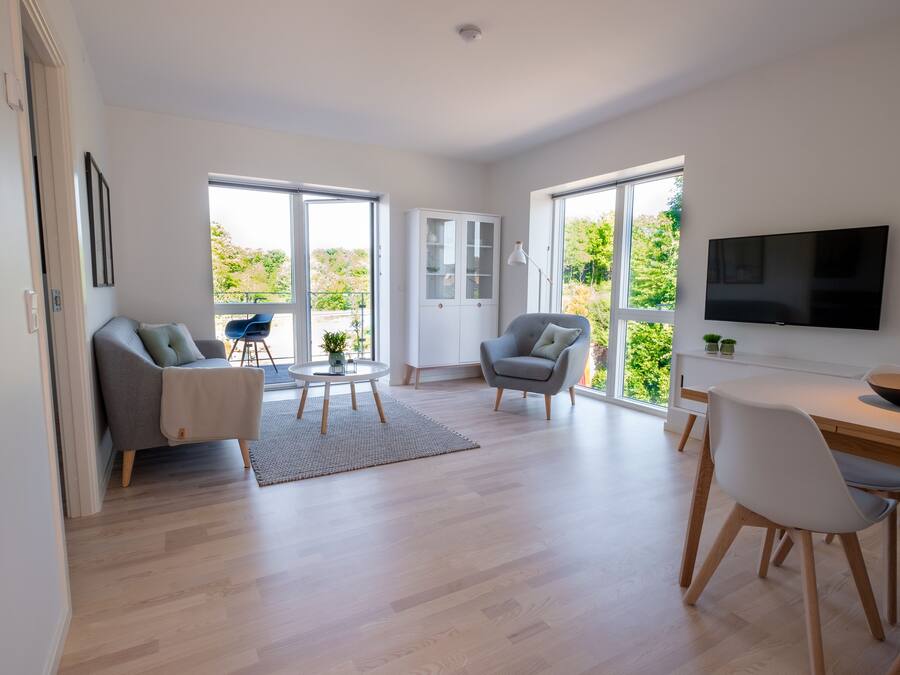 A modern living room with a sofa, chairs, a dining table, and a TV.