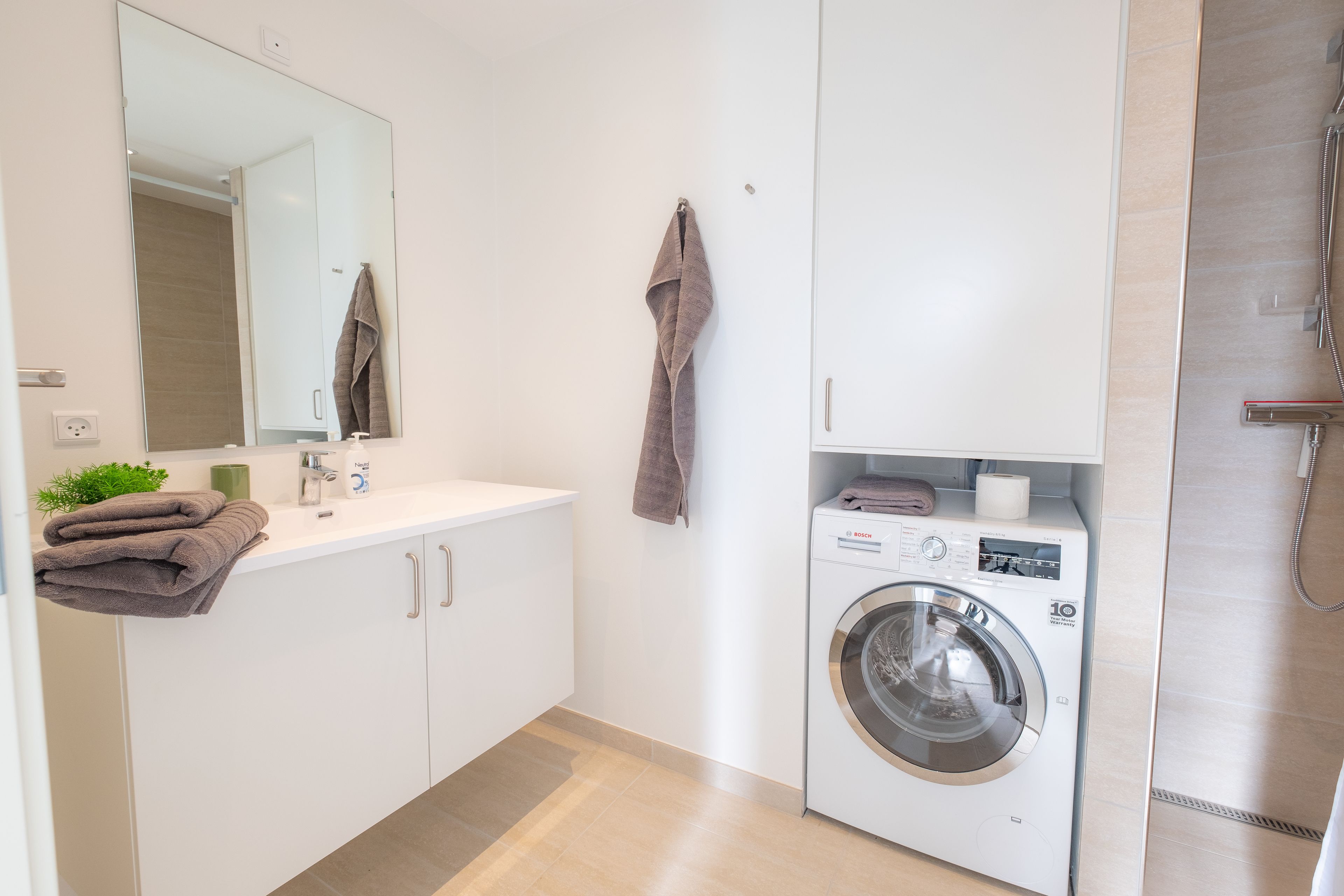 Un baño moderno con lavadora, lavamanos y espejo.