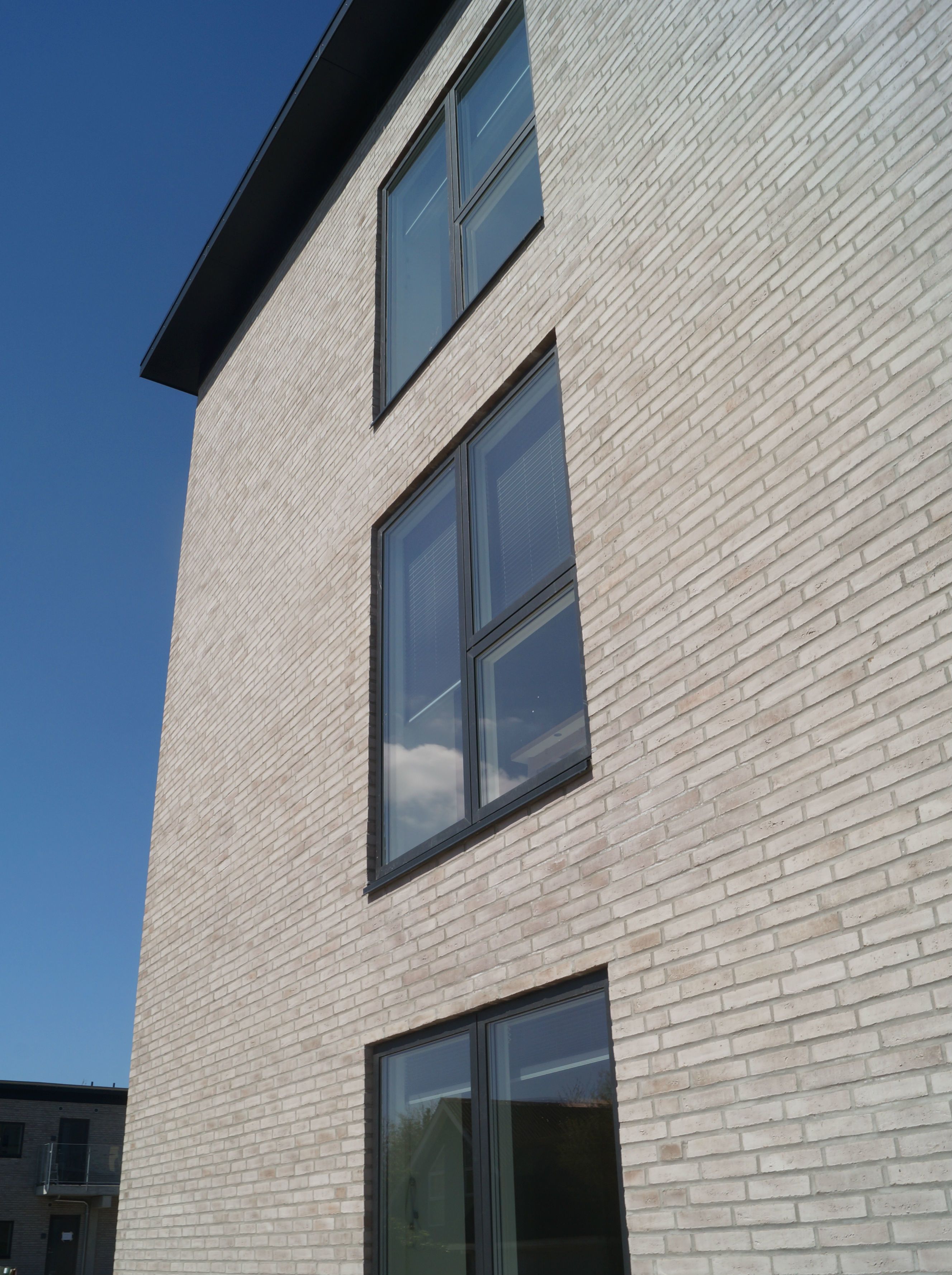 A modern building with a light-colored brick facade and large windows.