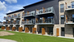 A modern multi-story building with balconies, outdoor seating, and a well-maintained lawn. - Aalborg Hotel Apartments (Aalborg)