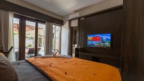 A hotel room with a bed, a TV mounted on the wall, and a view of the outside. - Villa Twin Lovina (Banjar)