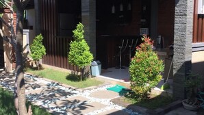 A modern building with a covered entrance, stone pillars, and a paved pathway leading to the entrance. - Villa Twin Lovina (Banjar)