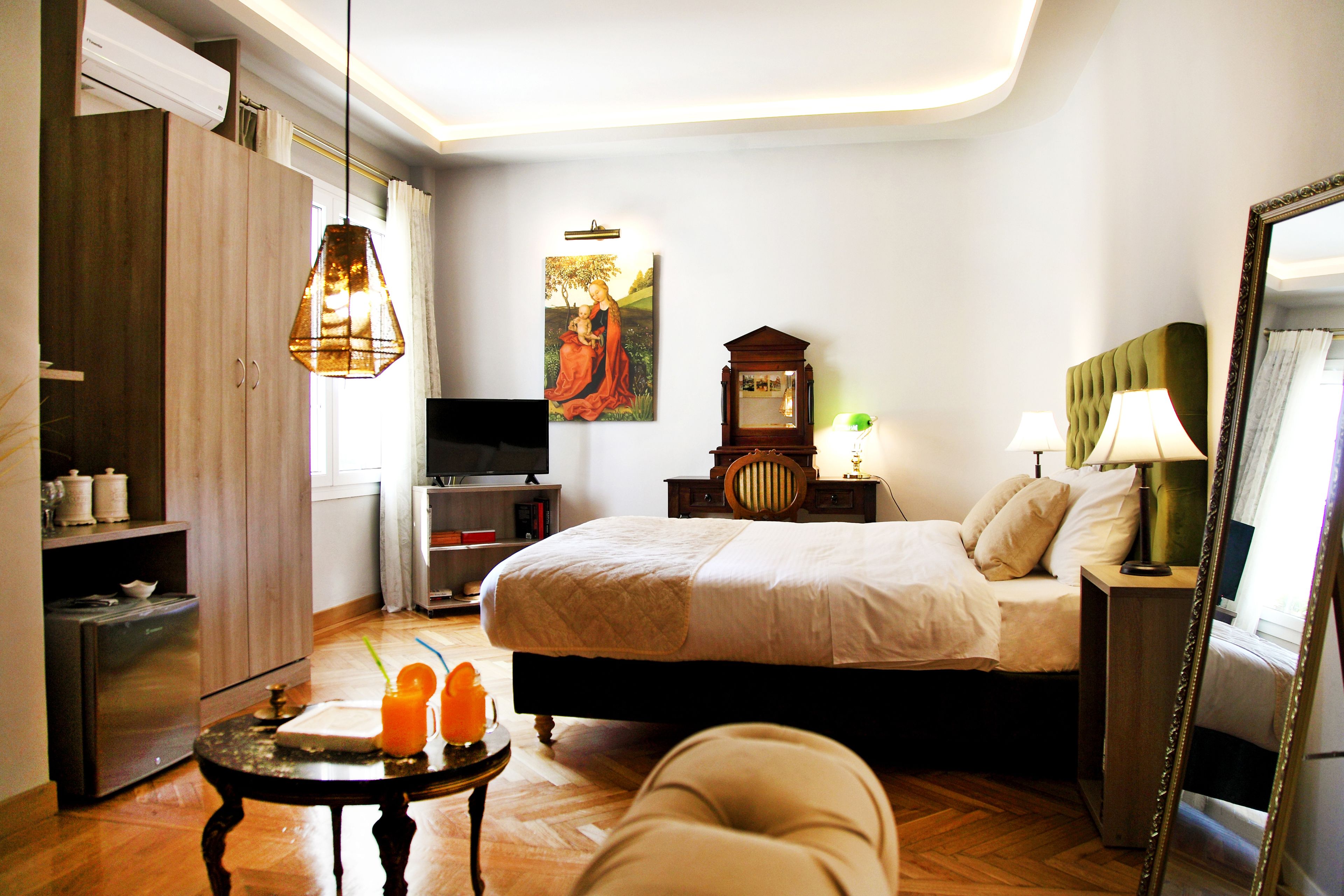 A bedroom with a bed, bedside table, lamp, and a mirror.
