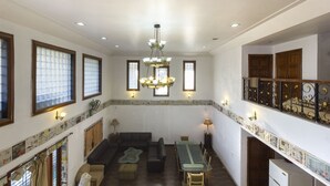 A spacious living area with a high ceiling, multiple windows, a chandelier, and a dining table with chairs. - GuestHouser 4 BHK Bungalow 7283 (Mawal)
