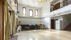 A spacious living area with a high ceiling, a dining table with chairs, a sofa, a dog statue, and a refrigerator. - GuestHouser 4 BHK Bungalow 7283 (Mawal)