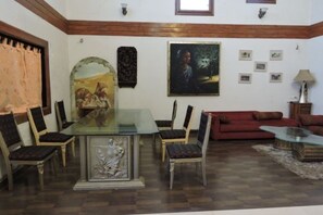 Un coin repas avec une table en verre entourée de chaises, un canapé rouge et un tableau accroché au mur.