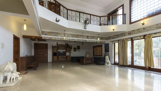 A spacious living area with a high ceiling, a wooden staircase, and a balcony with decorative railings. - GuestHouser 4 BHK Bungalow 7283 (Mawal)