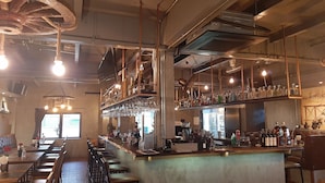 A bar area with multiple seating options, a bar counter with various bottles, and hanging lights. - Big Boys' Bed & Burger (Patong)