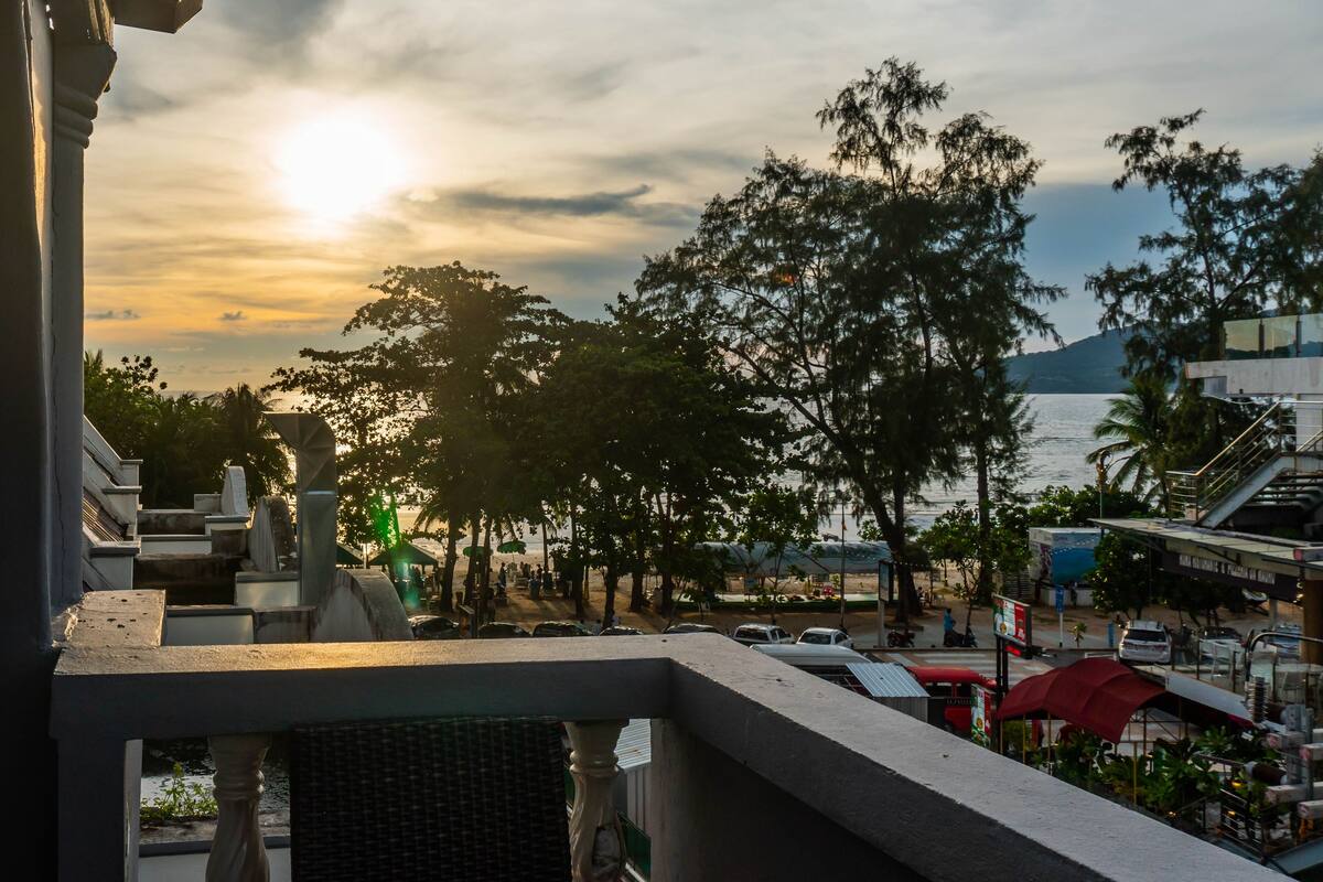 A view of a coastal area with a sunset, trees, and a body of water.