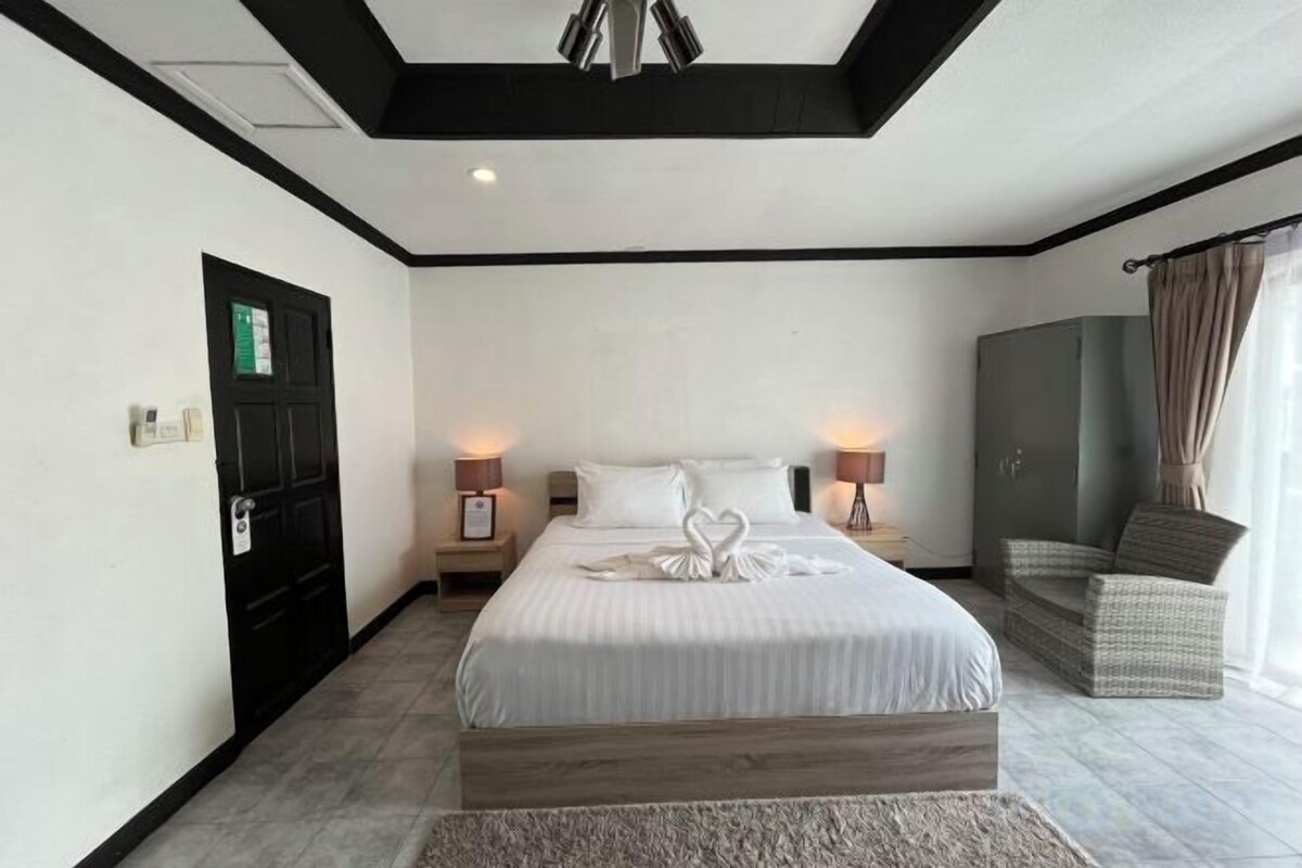 A hotel room with a bed, bedside lamps, a wardrobe, and a chair.