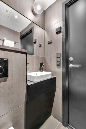 Uma casa de banho moderna com um espelho grande, uma pia e uma porta preta.