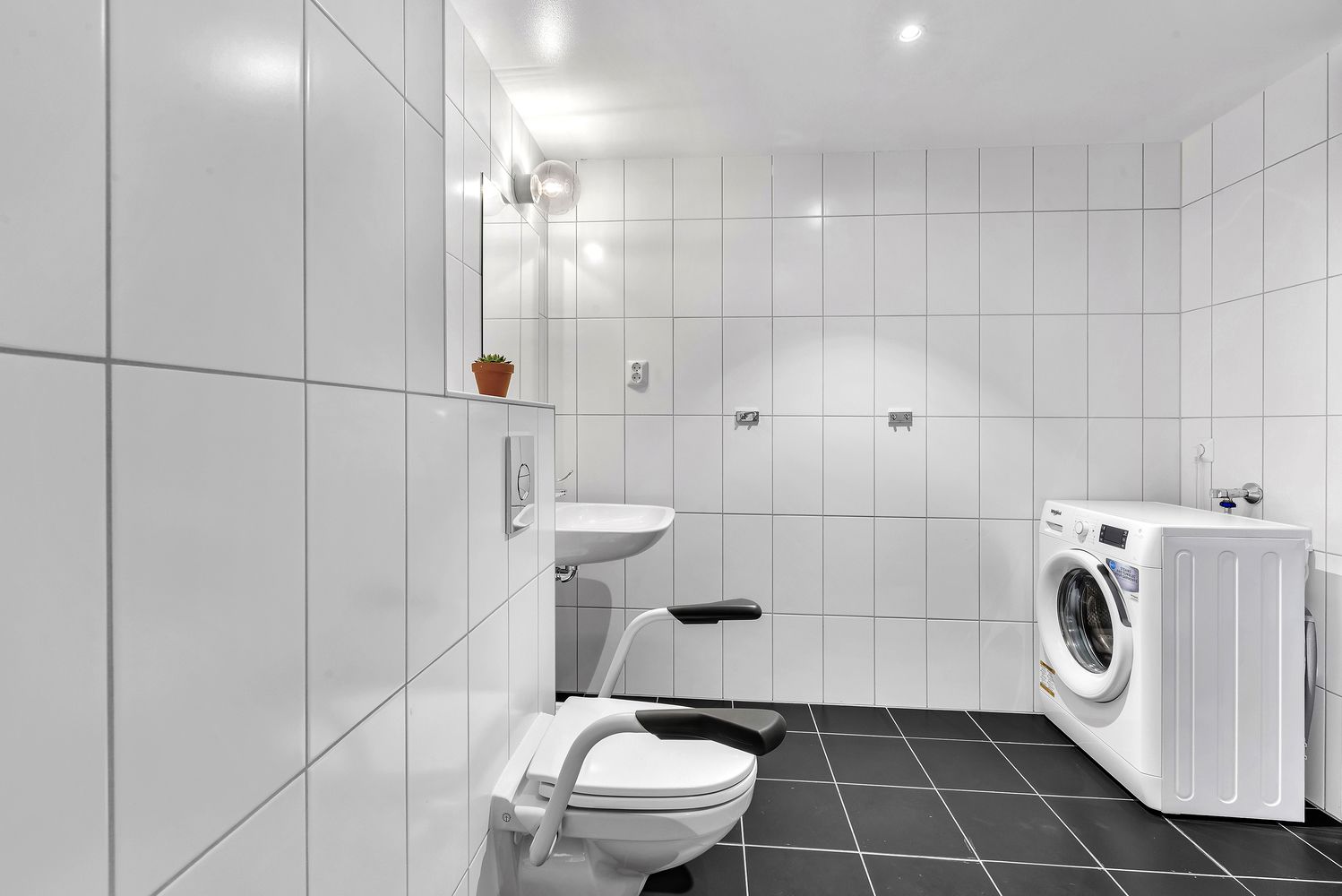 A modern bathroom with a toilet, sink, and washing machine.