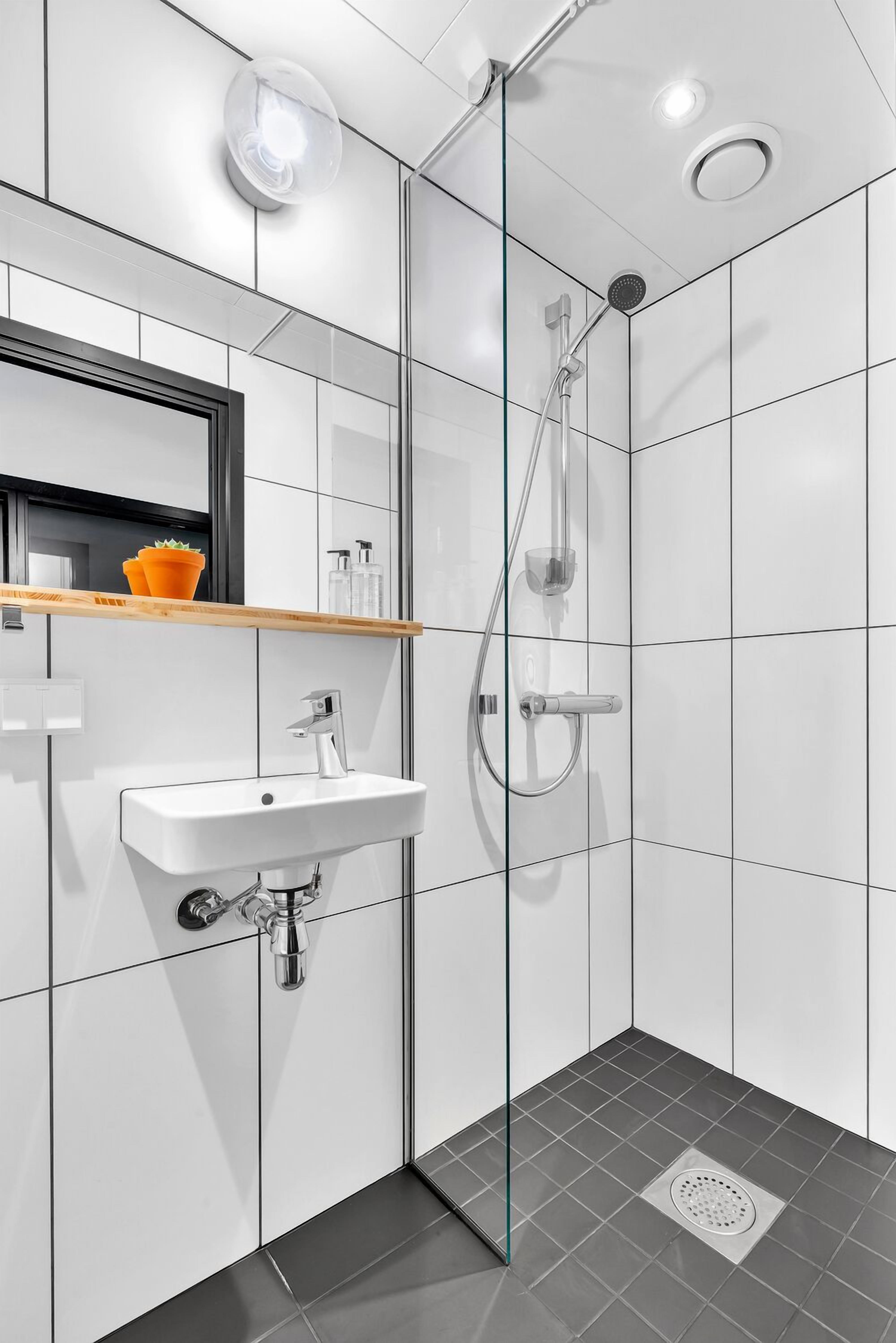Een moderne badkamer met een douchecabine van glas, een wit wastafelmeubel en een spiegel erboven.