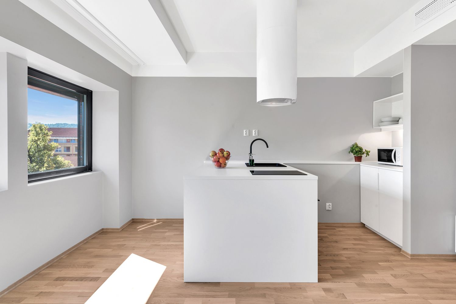 Une cuisine moderne dotée d’un îlot central, d’une fenêtre et offrant une vue sur l’extérieur.