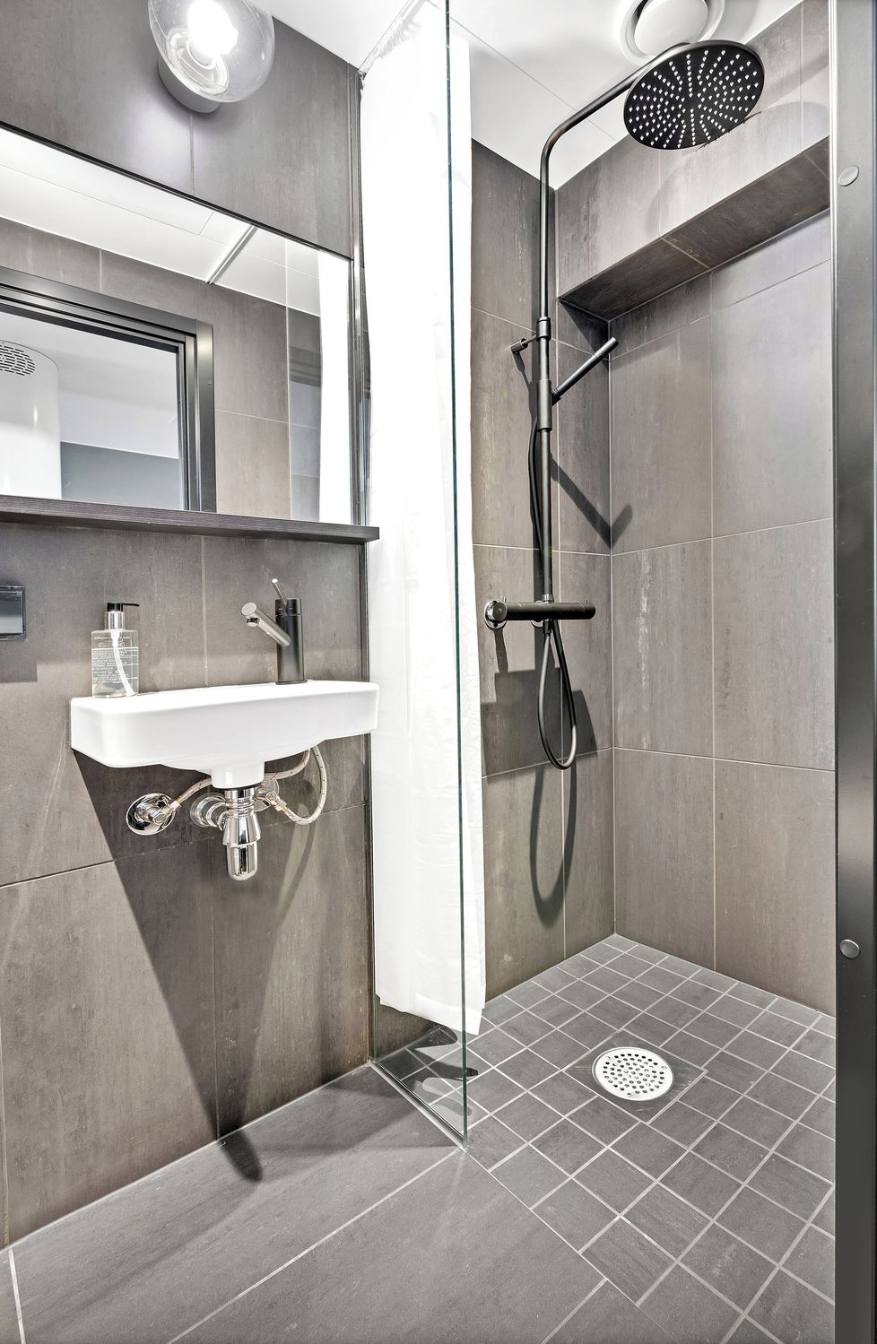 Un baño moderno con lavamanos integrado, cabezal de ducha de mano y mampara de ducha.