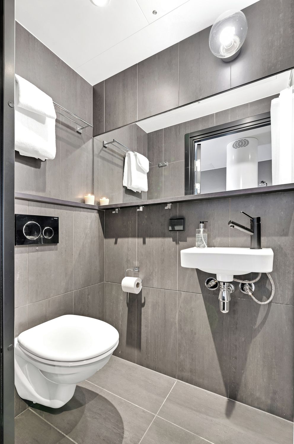 A modern bathroom with a white toilet, a sink with a mirror above it, and a towel rack.