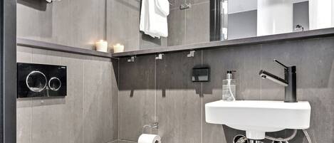 A modern bathroom with a white toilet, a sink with a mirror above it, and a towel rack.