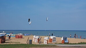 Une plage avec des chaises longues, des parasols et un filet de volley-ball.