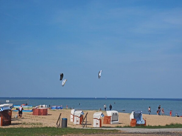 Una playa con sillas de playa, sombrillas y una red de voleibol.