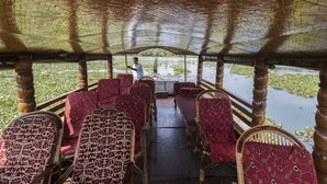 Un bateau abrité, doté de sièges à motifs rouges, et une personne se tenant à l’arrière.